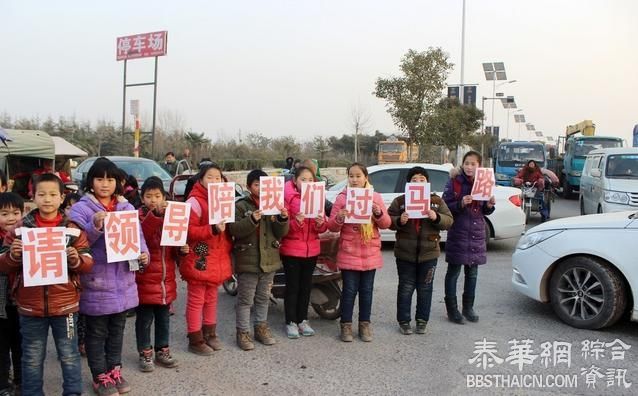 路口无红绿灯 学生举牌"请领导陪我们过马路"